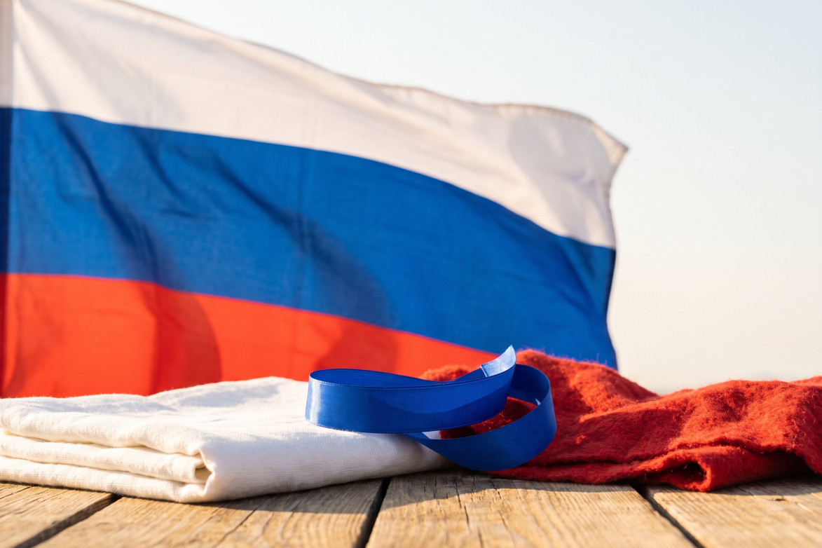 Государственный флаг России на флагштоке на фоне неба