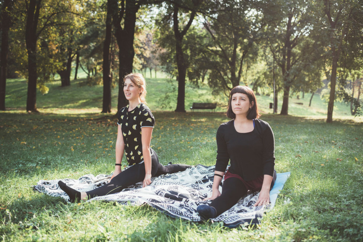 Две девушки сидят на шпагате в парке
