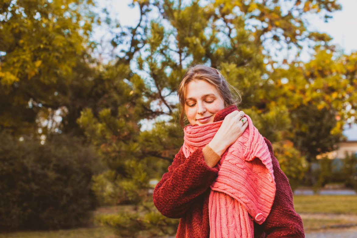 Девушка в осеннем парке кутается в шарф