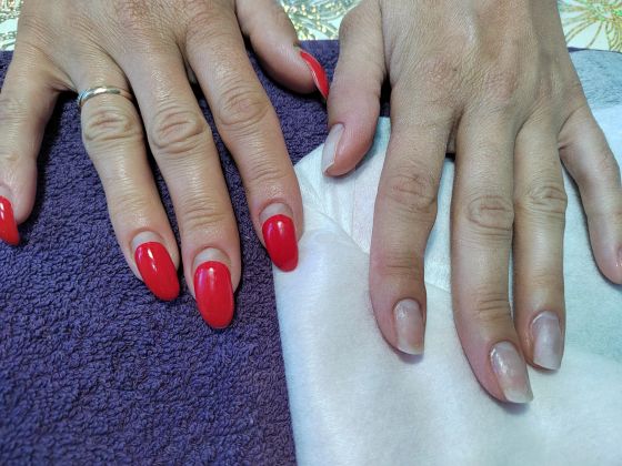 Маникюр с гель-лаком: яркие красные ногти и натуральный вид на другой руке.