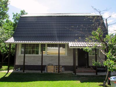 Дом из дерева. Крыша – металлочерепица, стены обшиты сайдинкгом (имитация кладки из камня).