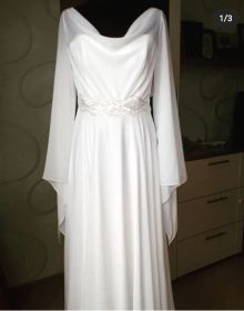 Свадебное платье пошито из шифона молочного цвета. Юбка-солнце, широкие ассиметричные рукава. По талии широкая вышитая кайма. 