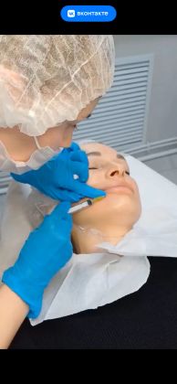 Косметолог проводит процедуру ухода за кожей лица.