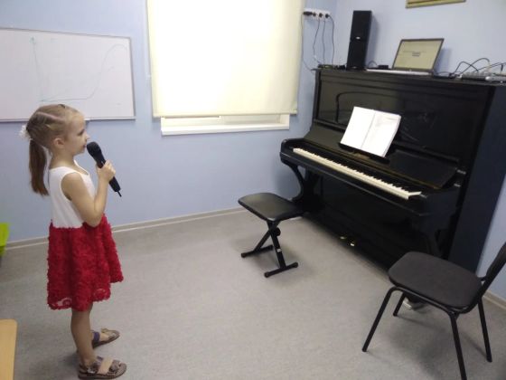 Ученица поет в микрофон на уроке вокала