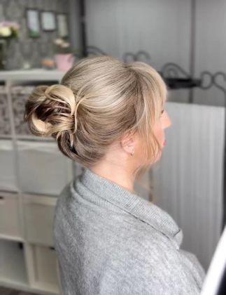 Парикмахер выполняет стрижку, сосредоточенно работает над волосами