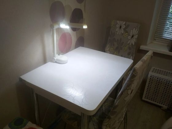 Рабочее место находится на кухне (стол и стулья), лампа для подсветки