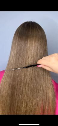 Парикмахер укладывает длинные светлые волосы, сосредоточенно работая.