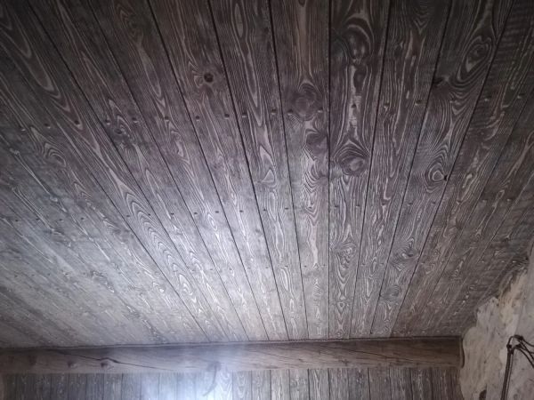 Готовый потолок, зашит брашированной и состаренной доской, места соединений закрыты декоративными деревянными заглушками, вместо галтелей уложили канат джутовый