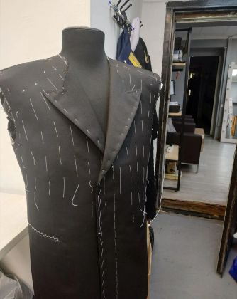 Пошив в процессе: ткань на столе, нити натянуты, швейная машина за работой.