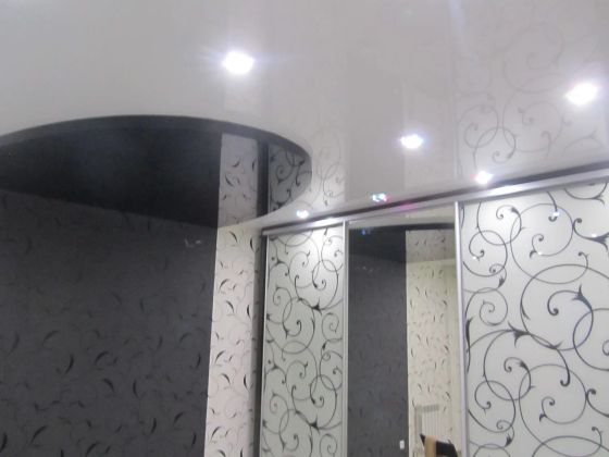 Двухуровневый потолок: черный глянцевый + белый глянцевый. Освещение: светильники с разноцветной подсветкой. Зона кровати выделена зеркальным черным глянцевым потолком