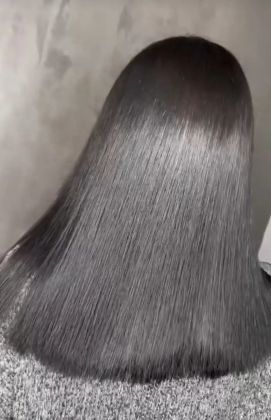 Парикмахеры создают гладкую укладку длинных темных волос