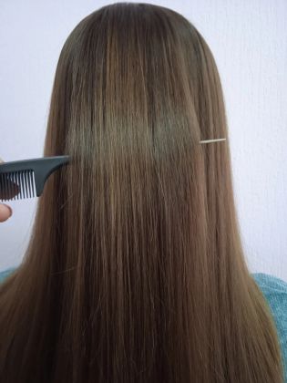 Парикмахер работает над длинными волосами клиента, формируя образ.