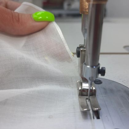 Пошив за швейной машиной: швея прокладывает строчку по ткани.