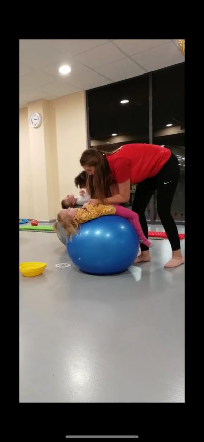 Дети занимаются фитнесом с тренером на гимнастическом мяче.