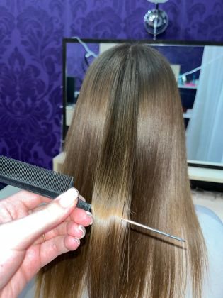 Парикмахер стрижет длинные волосы клиентке в салоне