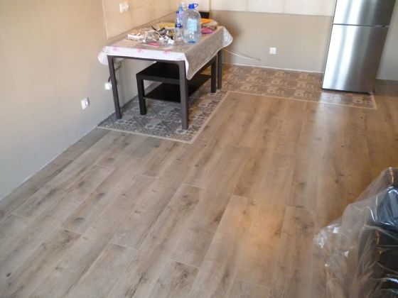 Выделение кухонной зоны с плиткой на полу под кухонные шкафы и укладка ламината