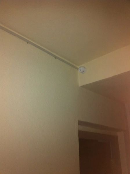 видеокамера купольного типа на этаже многоквартирного жилого дома с проводкой в кабельканале, подключённая к видеомонитору домофона