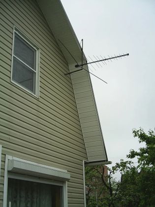Телевизионная всеволновая антенна на фасаде дачного участка