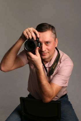 Фотограф за работой сосредоточенно снимает кадр камерой.