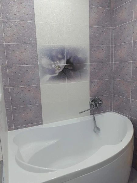 Ванная комната с угловой ванной, темный и светлый кафель, в центре  рисунок (цветы)