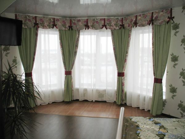 Комплект штор в спальню. Зеленые портьеры с обтачкой из цветочной ткани. Жесткий фигурный ламбрекен с милыми бордовыми бантиками, которые отлично сочетаются с подхватами.